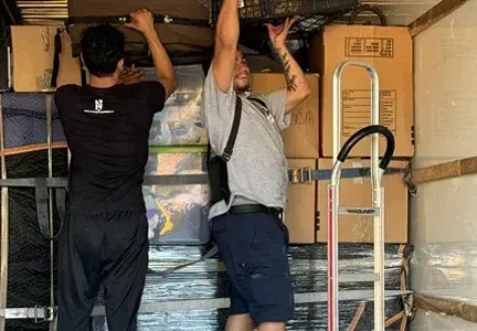 Two men are loading boxes into a moving truck.
