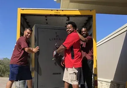 A group of men are loading a safe into a truck.