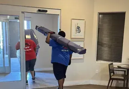 A man is carrying a large piece of furniture through a doorway.