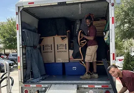 A man is standing in the back of a moving truck.