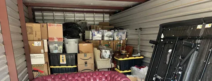 A storage unit filled with lots of boxes and a couch.