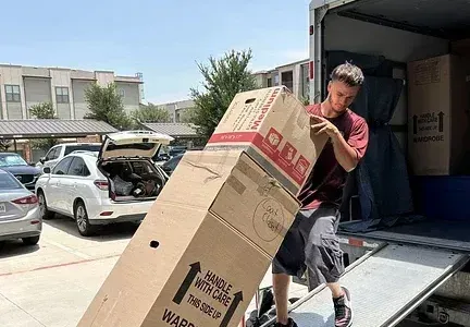 A man is loading a large cardboard box into a truck.