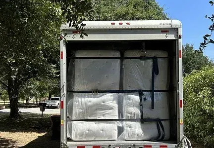The back of a trailer is filled with mattresses.