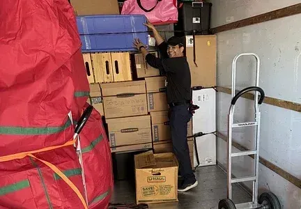 A man is loading boxes into a moving truck.