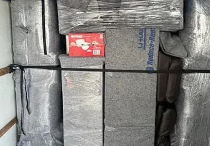 A bunch of boxes are wrapped in plastic and tied together in a truck.