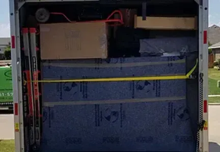 The back of a moving truck filled with boxes and a ladder.