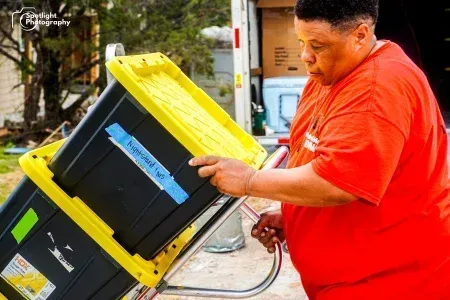 A man in a red shirt is pushing a cart with boxes on it.