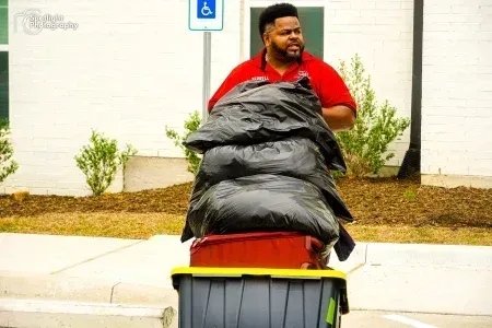 A man is pushing a cart full of trash bags.