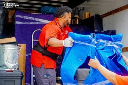 A man in a red shirt is holding a blue tarp.