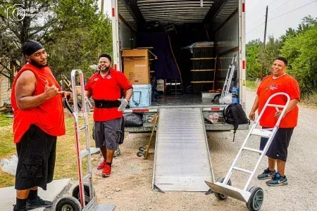 Three men are standing in front of a moving truck.