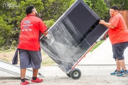 Two men are carrying a large box on a dolly.
