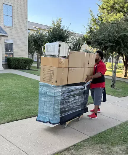 A man is pushing a cart filled with boxes on a sidewalk.