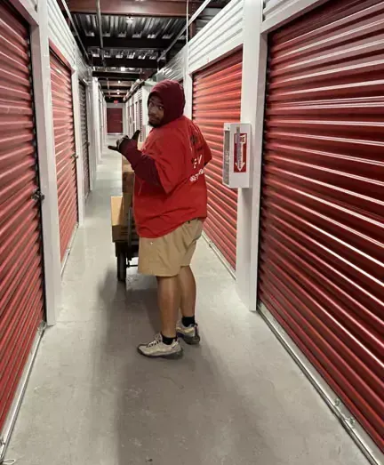 A man in a red shirt is standing in a hallway with red shutters.