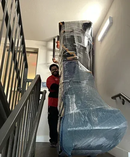 A man is carrying a large piece of furniture up a set of stairs.