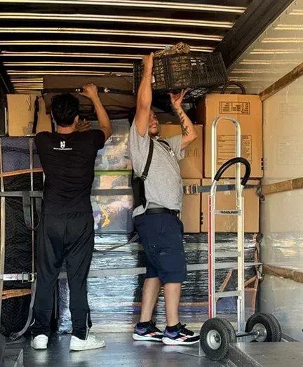 Two men are loading boxes into a moving truck.