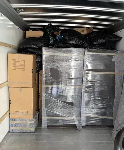 The inside of a moving truck filled with boxes and bags.