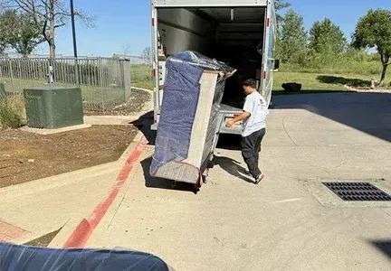A man is pushing a refrigerator out of a moving truck.