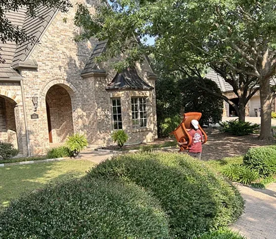 A man is carrying a large object in front of a house.