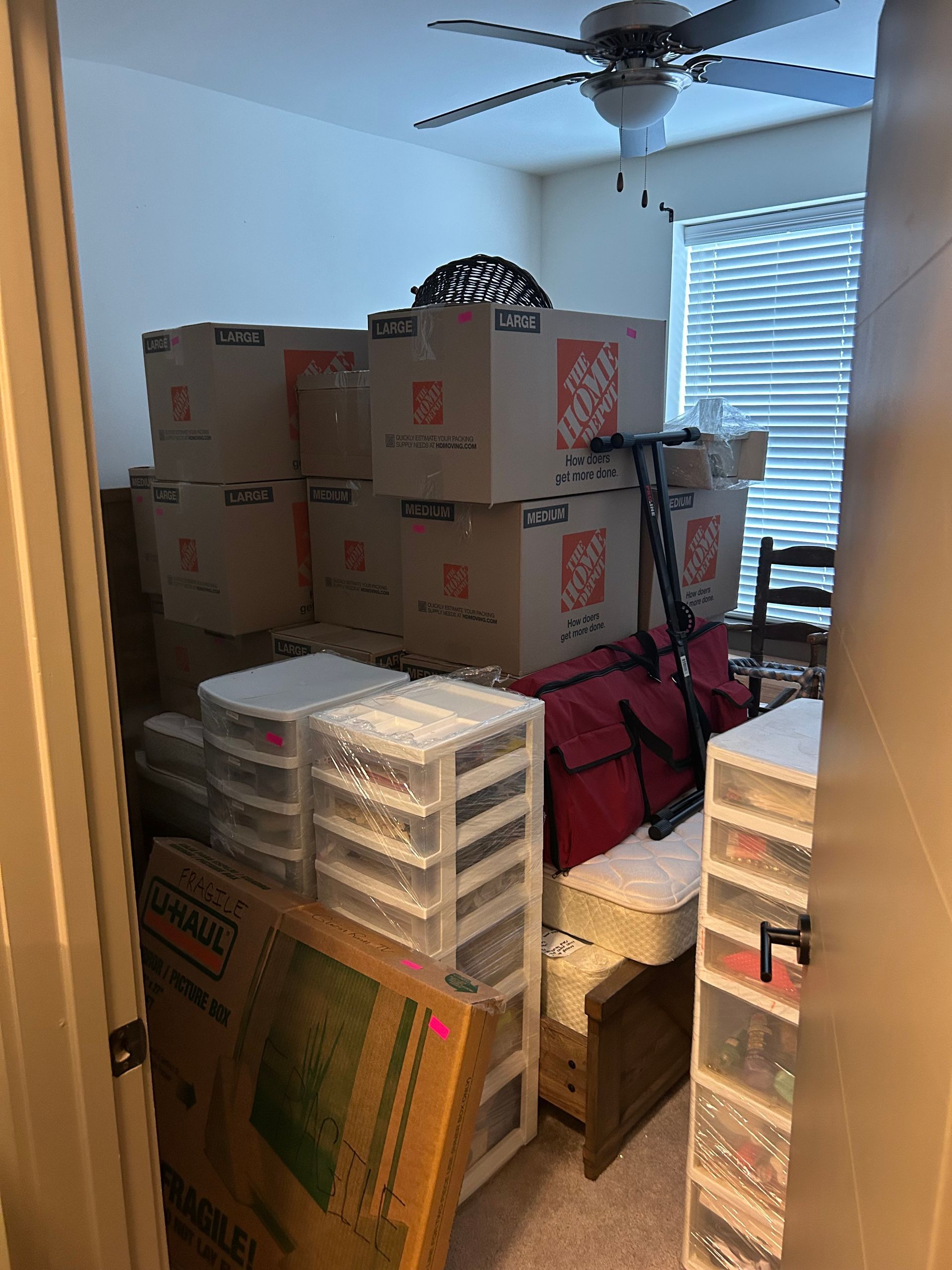 A man is pushing a cart full of boxes down a sidewalk.