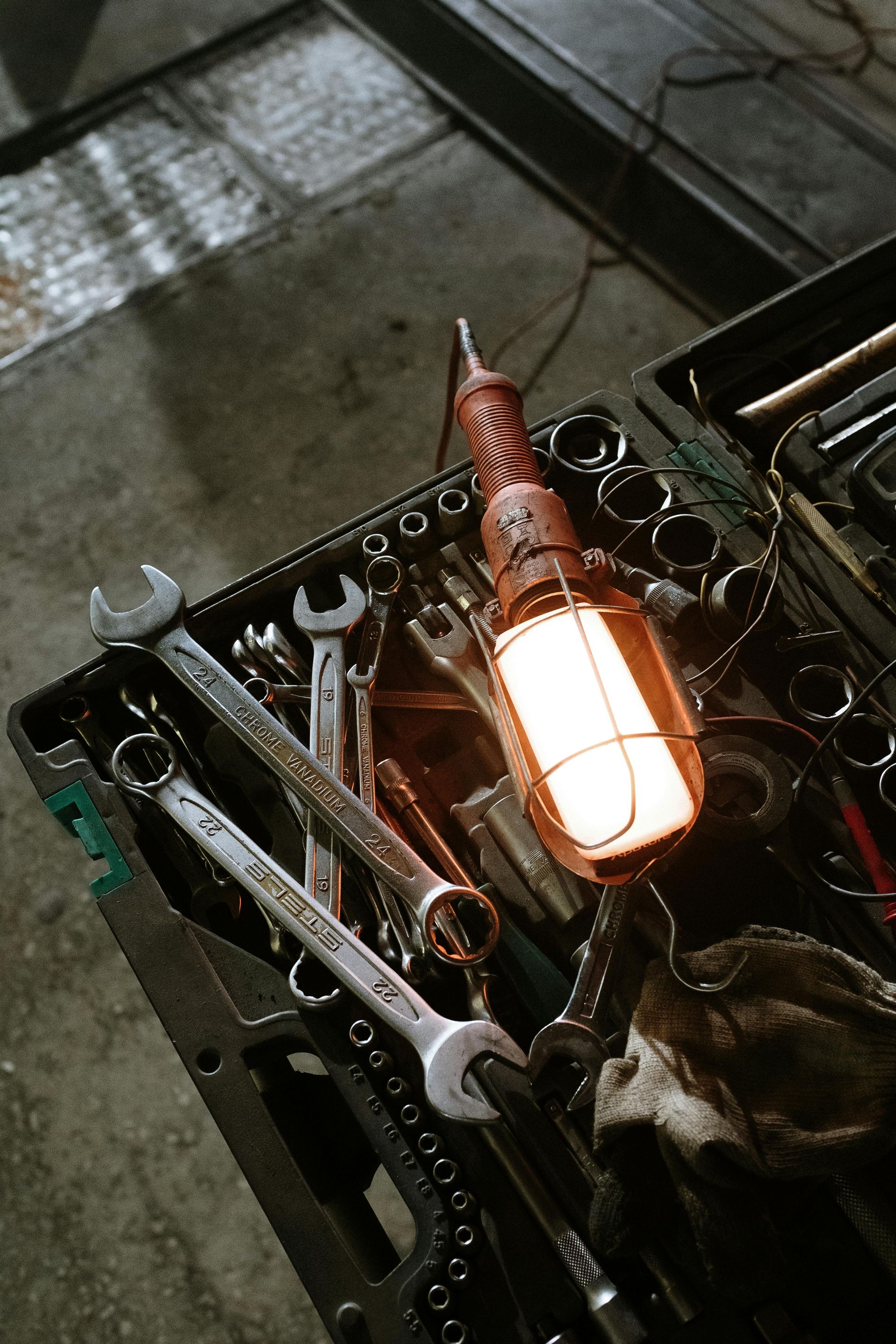 Toolbox with wrenches and sockets, lit by a work lamp, set in a garage.