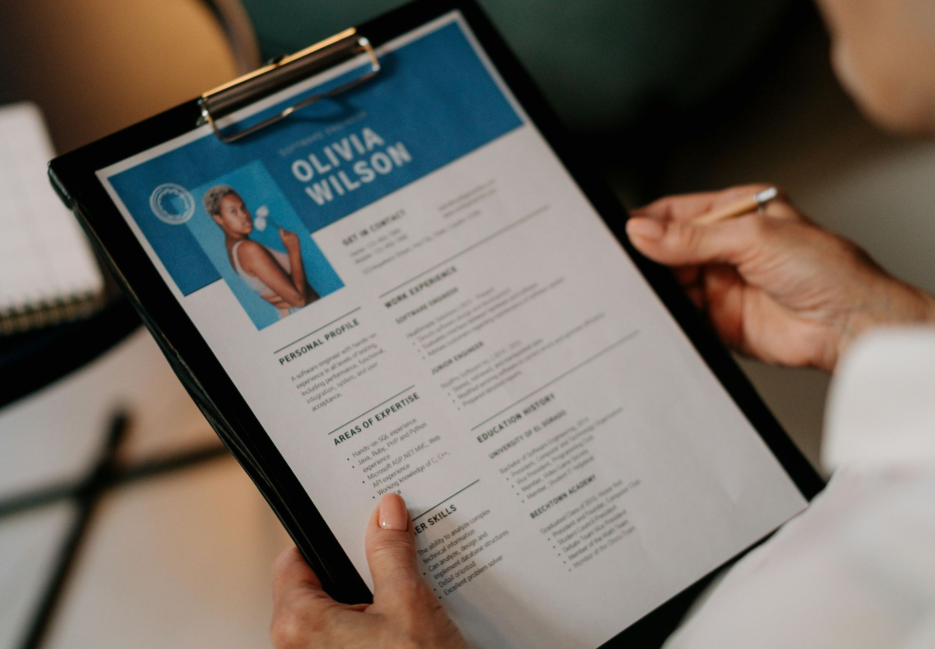 Person holding resume of Olivia Wilson, blue and white design.