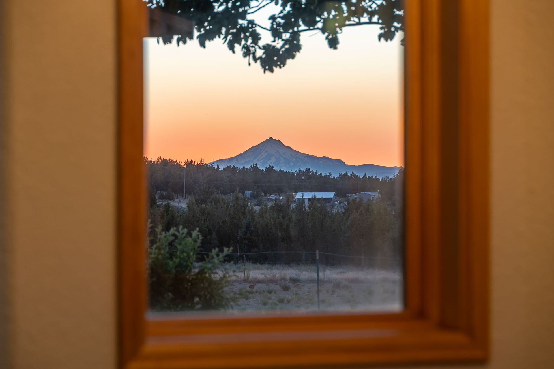 A view of a mountain through a window at sunset