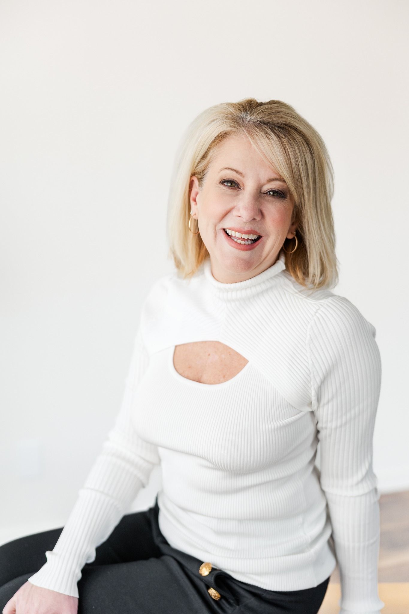 A woman in a purple shirt is holding a black briefcase and smiling.