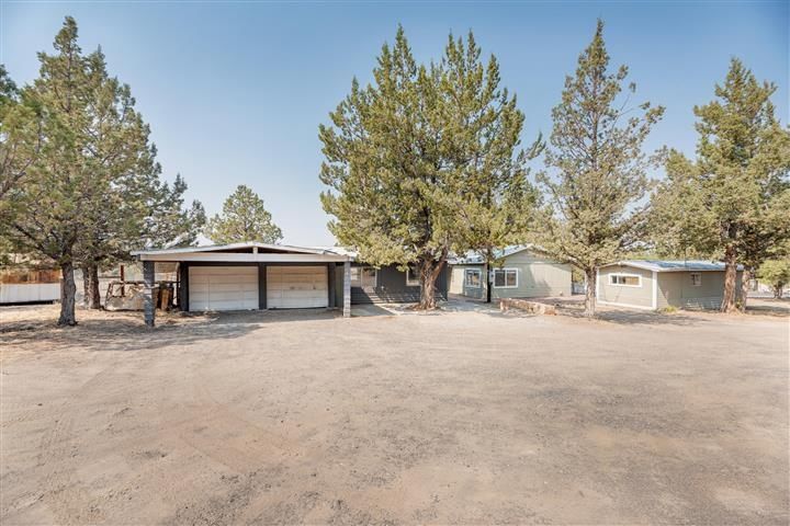 A house with a garage and trees in front of it.
