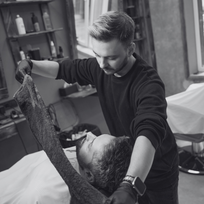 A man is giving a man a haircut in a black and white photo.