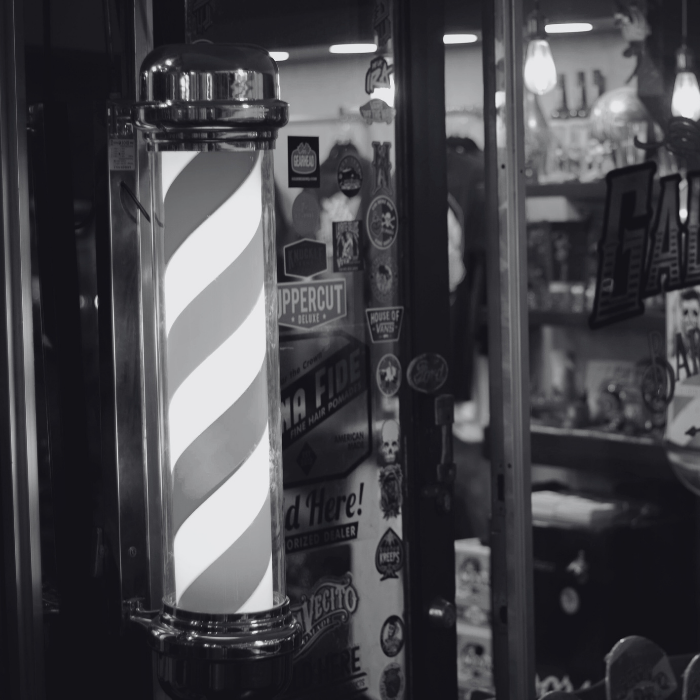 A black and white photo of a barber pole in a barber shop.