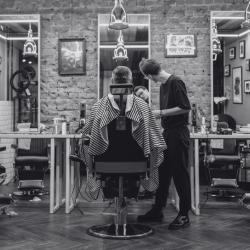 A man is cutting a man 's hair in a barber shop