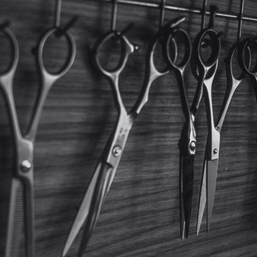 A black and white photo of scissors hanging on a wall
