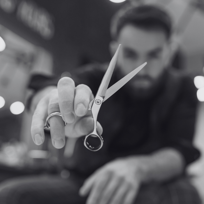 A black and white photo of a man holding a pair of scissors