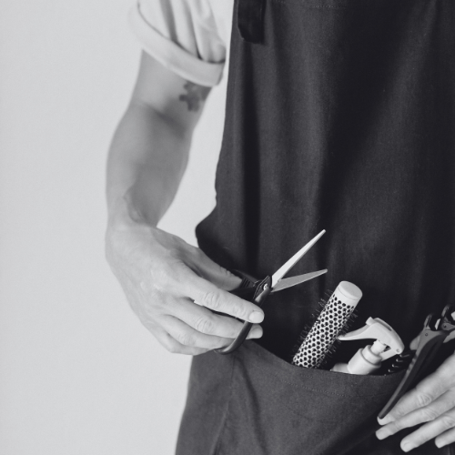 A black and white photo of a person holding a pair of scissors