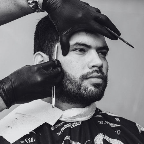 A man is getting his beard trimmed by a barber