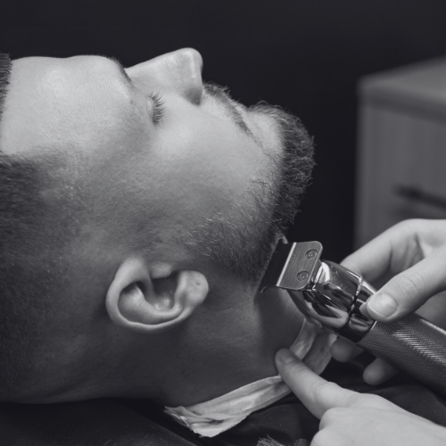A man is getting his beard trimmed by a barber
