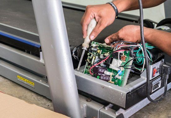 Worker Fixing the Treadmill — Brick, NJ — Ocean Fitness Equipment Worker Fixing the Treadmill — Brick, NJ — Ocean Fitness Equipment