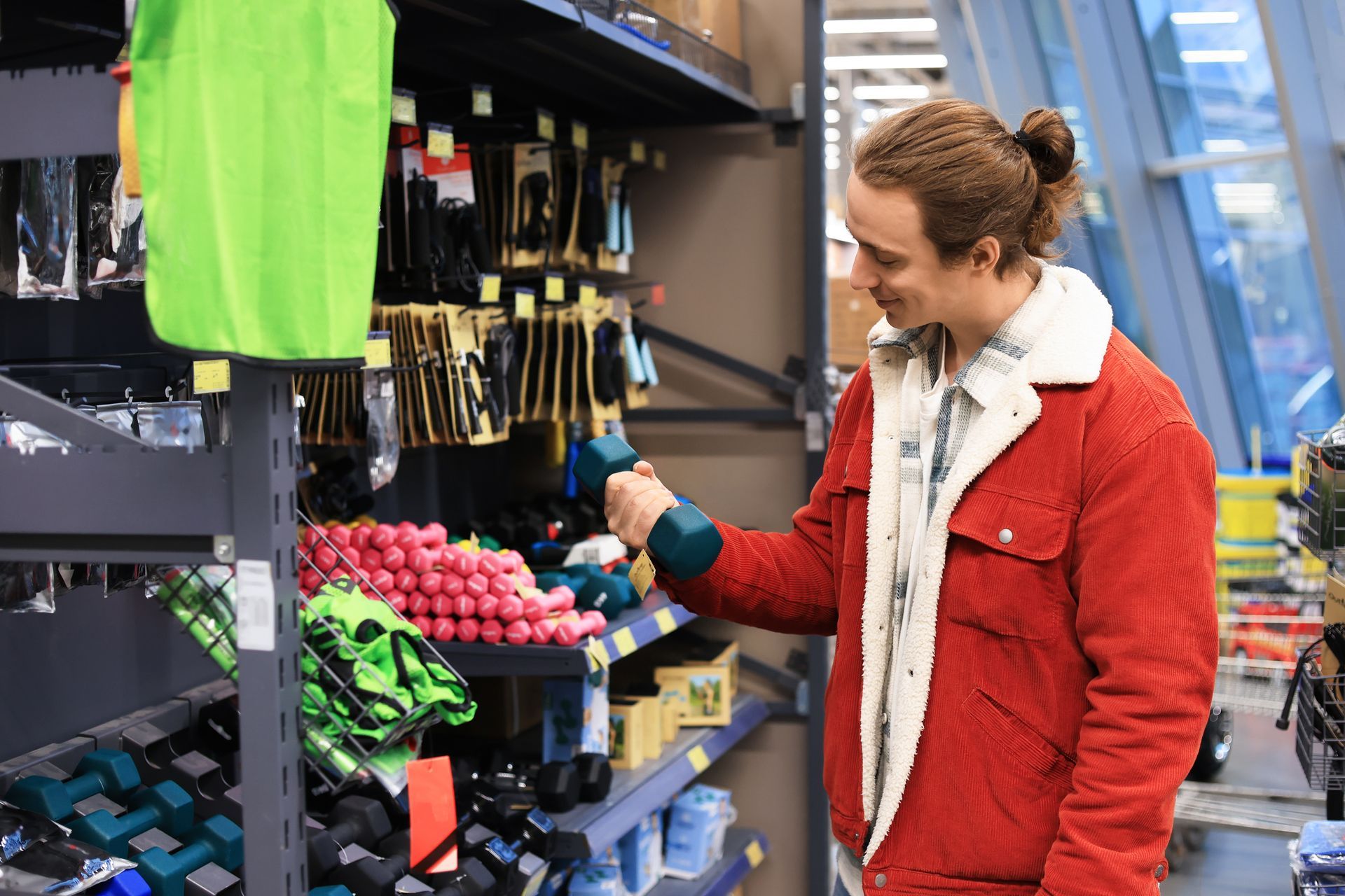 Man holding dumbbell inside gym equipment store browsing free weights and fitness gear. Man holding dumbbell inside gym equipment store browsing free weights and fitness gear.
