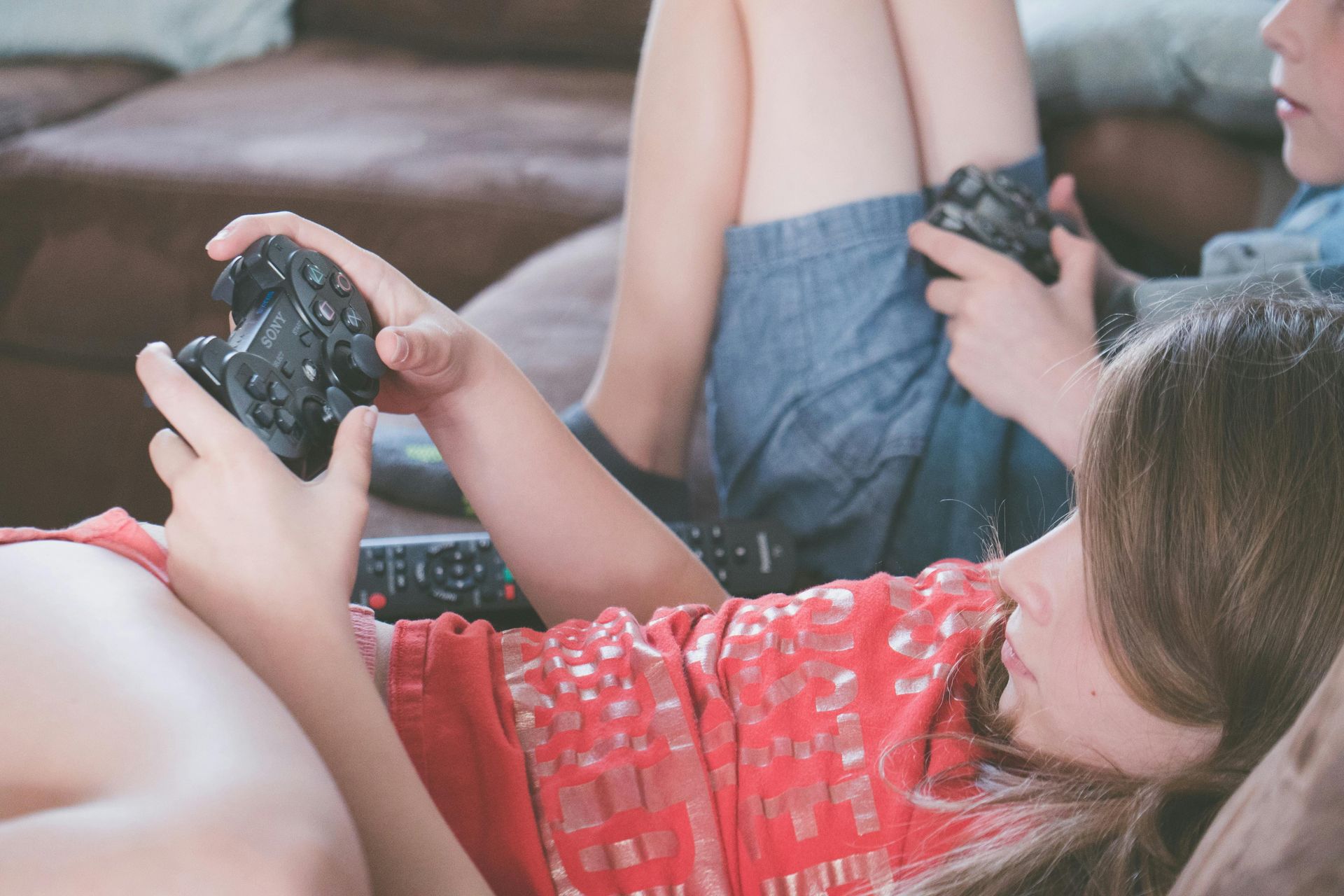 A boy and a girl are laying on a couch playing a video game.