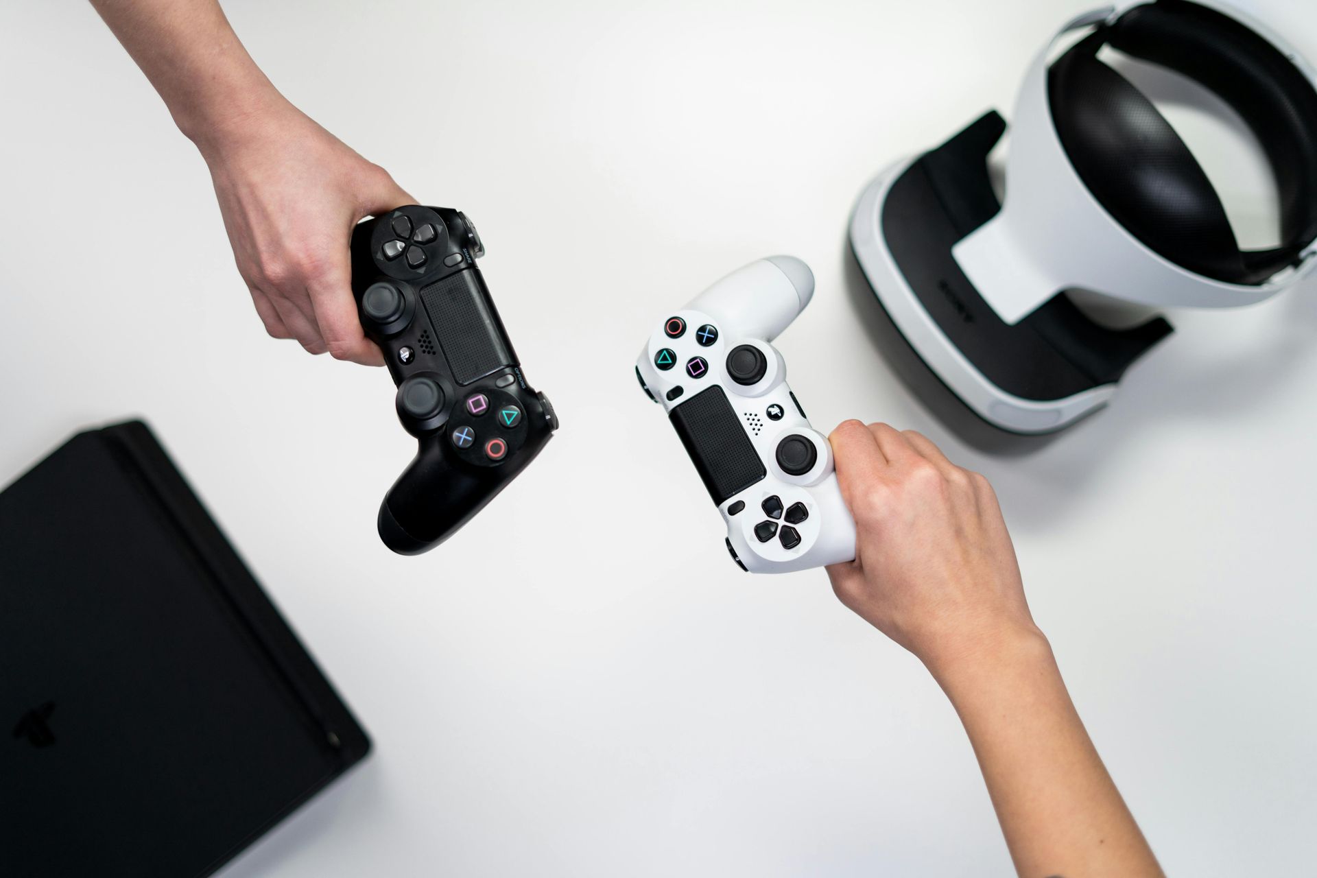 A person is holding a video game controller next to a virtual reality headset.
