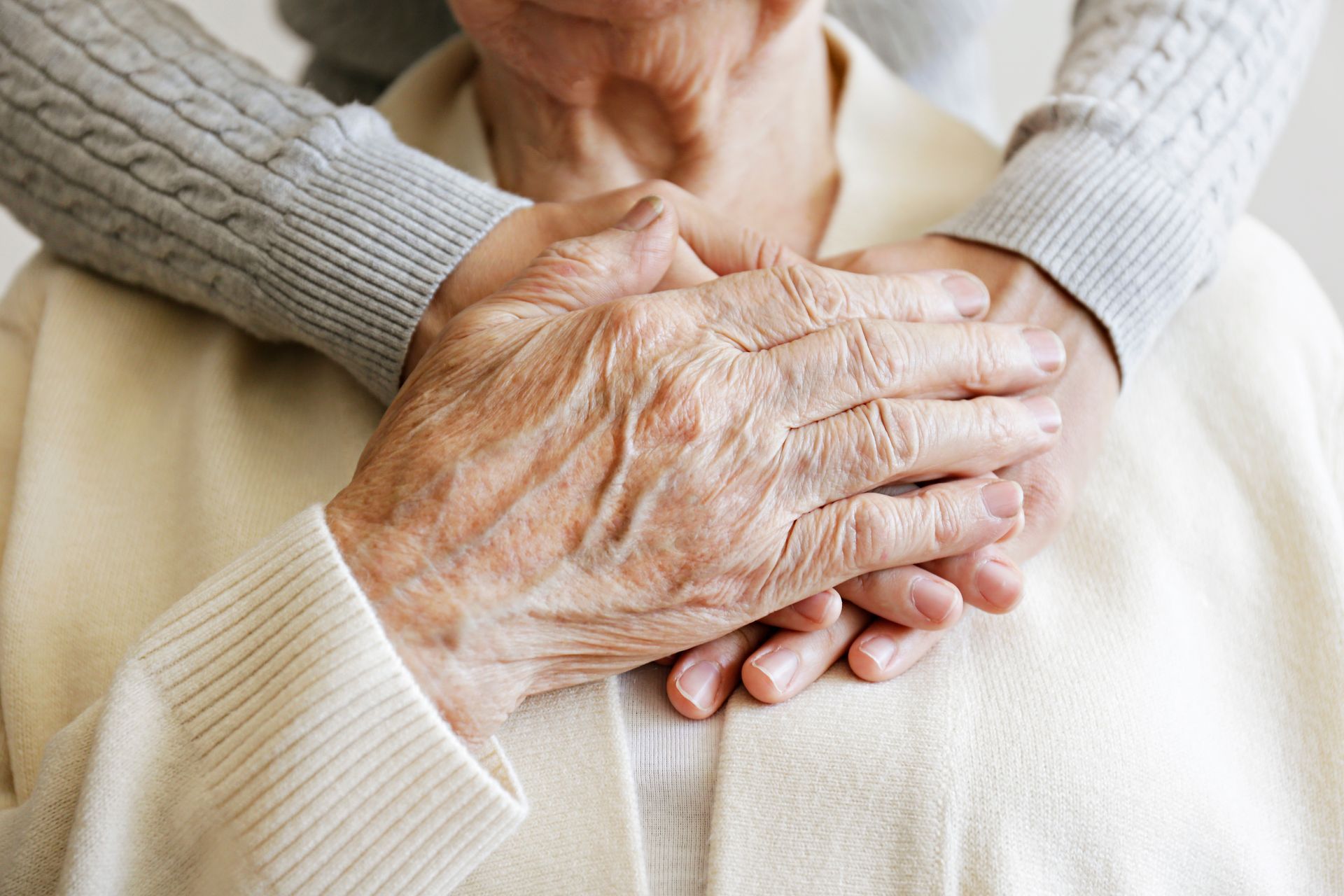 A woman is holding an older woman 's hand on her chest.