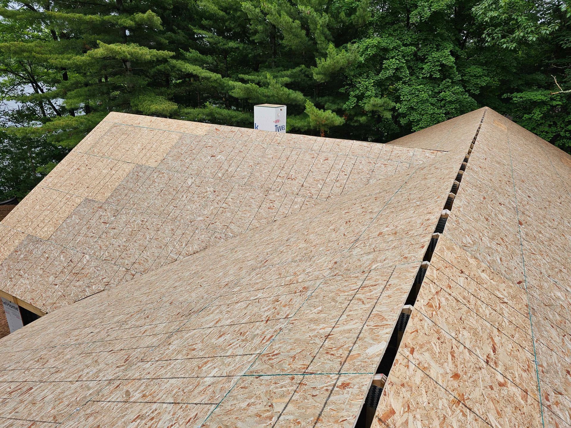 A man diligently repairs a roof, hammer in hand, surrounded by tools and roofing materials.