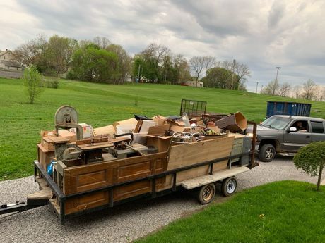 a truck is pulling a trailer full of junk on a gravel road .