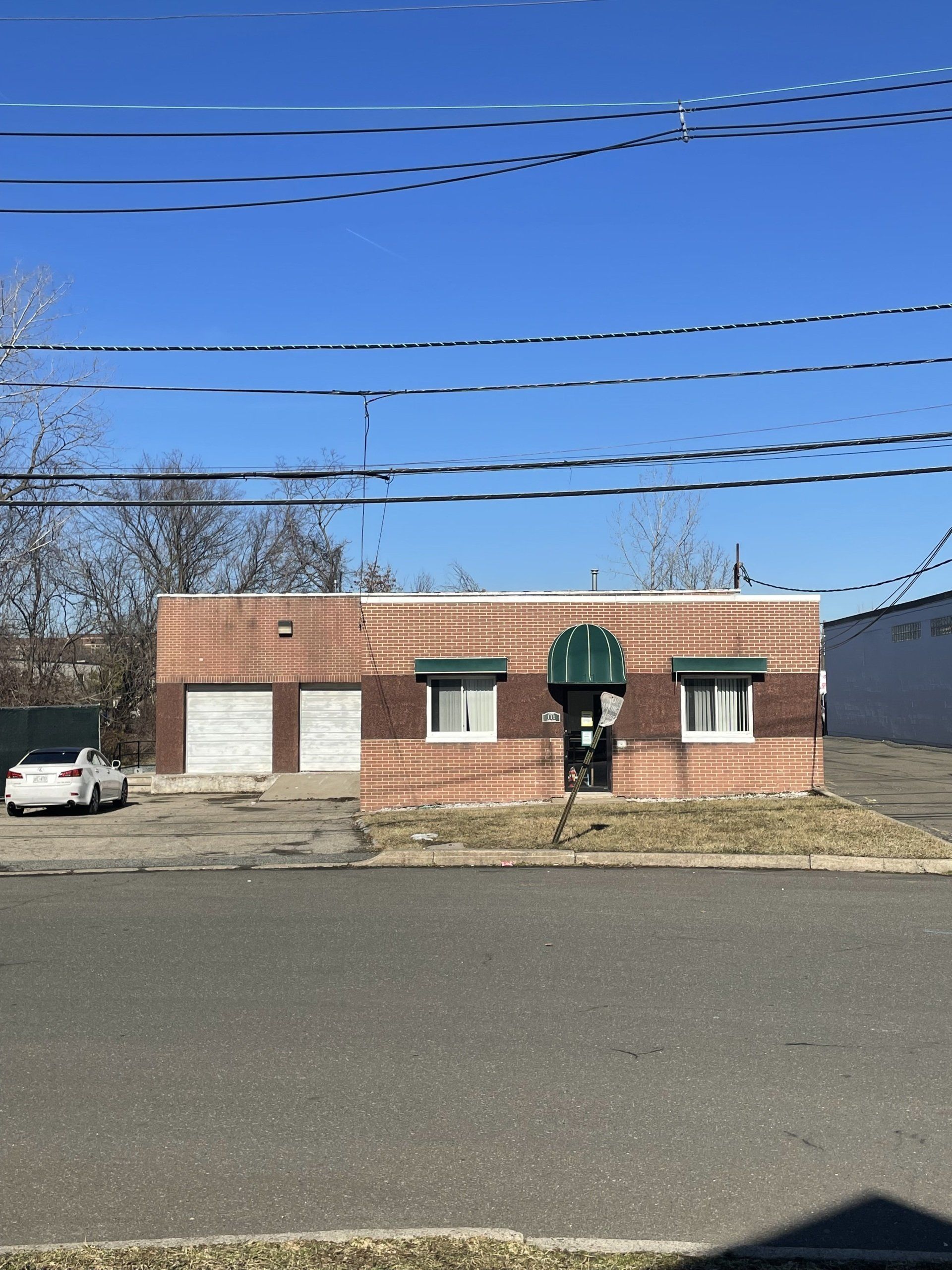 Exterior of 111 Cedar Lane, Englewood, NJ - 1 Unit. Brick one-story building with green awnings over windows..