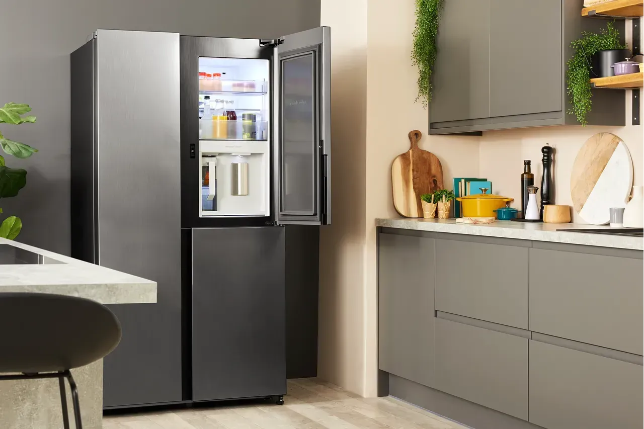 A black refrigerator is sitting in a kitchen with its doors open.