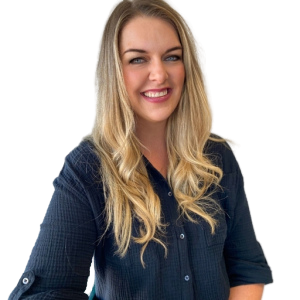 Woman with long blonde hair smiles, wearing a black button-down shirt, near a window.