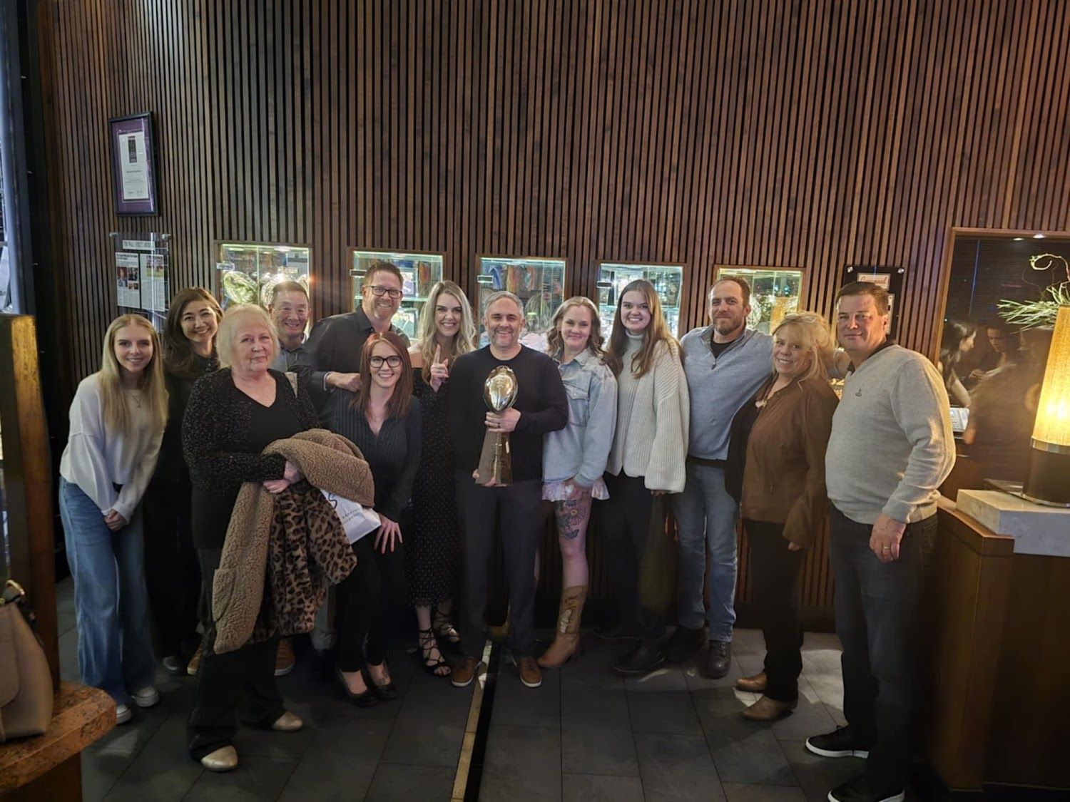 Man with short hair and stubble, smiling, wearing a blue button-down shirt.