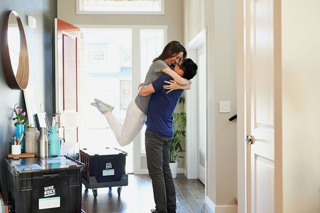 Couple embracing in a bright hallway, one person lifting the other off the ground.
