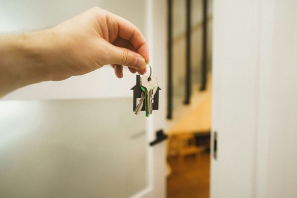 Hand holding a set of keys in front of an open doorway