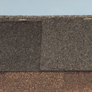 Dark gray and brown layered roofing shingles with a straight horizontal seam